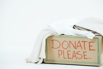 cardboard box with inscription and donated clothes on white