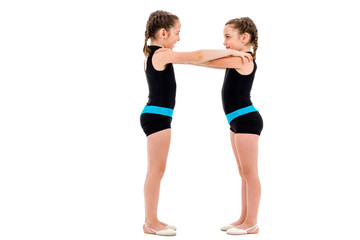 Identical twin girls practice and doing rhythmic gymnastics, white background.
