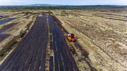 Aerial view machinery harvesting peat bog during early summer in rural Ireland
