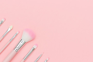 Set of pink makeup brushes on pastel pink background