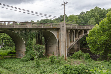Fototapeta na wymiar Vintage stone block bridge over a river surrounded by lush vegetation