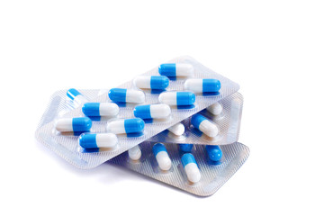 pile of blister packs with blue and white capsules isolated on white background - obrazy, fototapety, plakaty