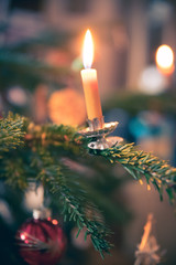 Candle on traditional decorated Christmas tree, evening