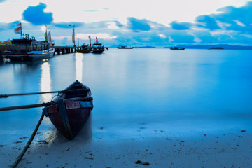 Long exposure shot of the ocean and a pier in a blue time with the old boats defocused. uploaded at Bandar Lampung. Indonesia in May 2019. Traveling concept