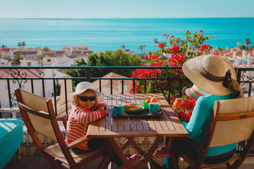 family having breakfast on balcony terrace with sea view