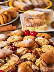 Oatmeal cookies and sand chocolate cake with cherry berry and crispy wafer rolls with cream on cutting board on wooden table in rustic style. Still life served. Delight pleasant taste.
