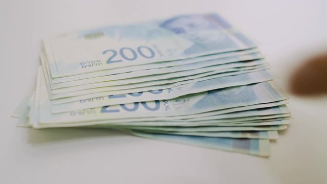 Stash of Israeli 200 shekel bills is put on table and then taken