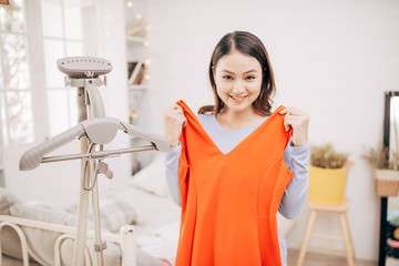Beautiful young asian woman smiling with clothes trying on dress up fitting with modern in the room