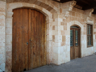 Fototapeta na wymiar Wooden gates, barred door and window of antique stone building