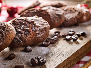 Oatmeal chocolate cookies with coffee grains and cherry, powdered sugar on kitchen cutting board with checkered fabric on wooden table in village style for picnic. Optimal level of glucose in blood.