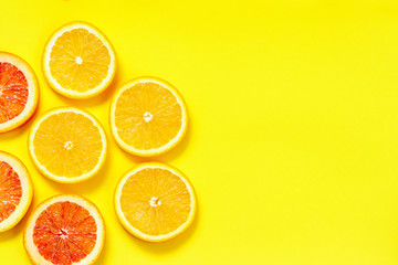 Citrus slices pattern on yellow background from above. Top view of orange and grapefruit fruit slices on yellow background. Fruit summer cocktail pattern design