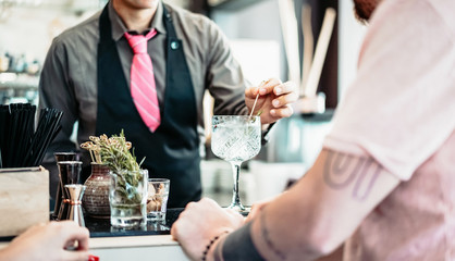Bartender preparing gin tonic cocktail - People having fun in american bar waiting for barman serving drinks - Concept of youth lifestyle and bar entertainment