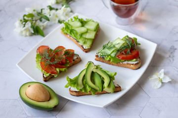 Vegetarian sandwiches with avocado, tomatoes and cucumbers on a light background