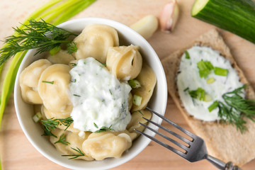 boiled dumplings with sour cream and herbs in a plate