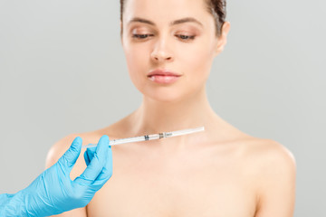 cropped view of cosmetologist holding syringe near naked woman isolated on grey