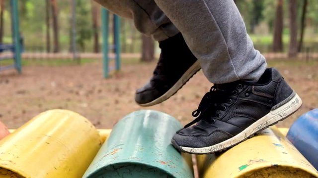 boy in sneakers runs on a treadmill on the playground in the open air