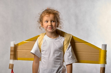 Little girl with wings laughing on grey background