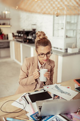 Designer drinking coffee and looking at her sketches.