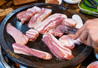 Pan-fried black pork meal in Korea restaurant, fresh delicious korean food cuisine on iron plate with lettuce, close up, copy space, lifestyle
