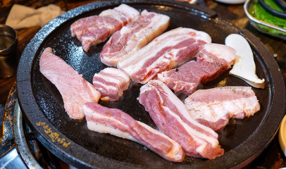 Pan-fried black pork meal in Korea restaurant, fresh delicious korean food cuisine on iron plate with lettuce, close up, copy space, lifestyle