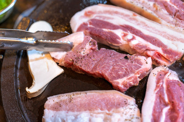 Pan-fried black pork meal in Korea restaurant, fresh delicious korean food cuisine on iron plate with lettuce, close up, copy space, lifestyle