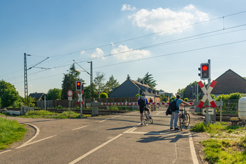 Outdoor sunny view of peoples after work commute and stop at level crossing railway barrier wait...