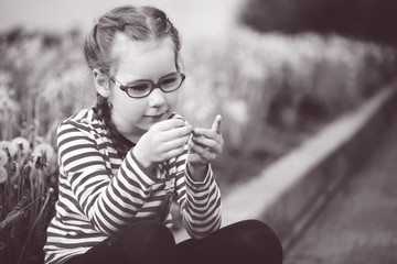 beautiful emotional girl with glasses playing with dandelions. childhood concept