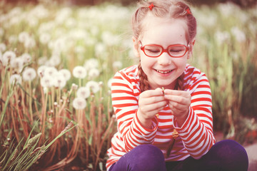 beautiful emotional girl with glasses playing with dandelions. childhood concept