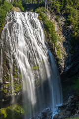 Obraz premium A large drop waterfall photographed on a long exposure to create blurred motion to the water, the Narada Waterfall, Mount Rainier National Park, Washington State, USA. nobody in the image