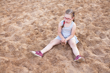 girl with glasses sitting on the sand