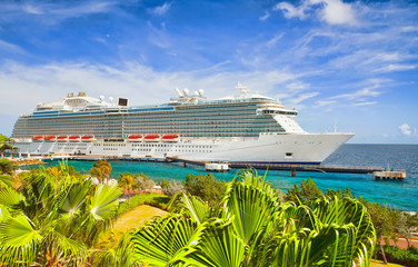 Cruise ship docked at tropical island on sunny day