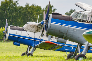 Two soviet aircrafts biplane Antonov AN-2 parked on a green grass of airfield closeup