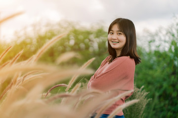Asian woman Standing smiling in the fields of brown grass in the morning sun With a happy face
