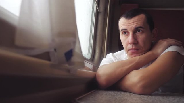 man sad bored riding a train railway looks out lifestyle the window. traveler concept train railroad journey travel. slow motion video. beautiful from window of a moving train railway trip Russia