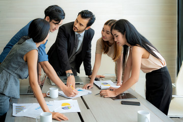Smart manager explaining internal meeting to his project team in modern office. The multi ethnic...