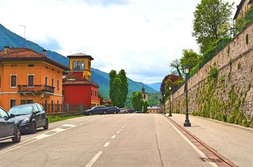 roadway of the Central part of the city leading along the stone wall and houses, with parked cars