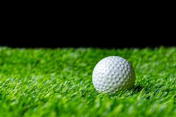 Golf ball on grass in black background