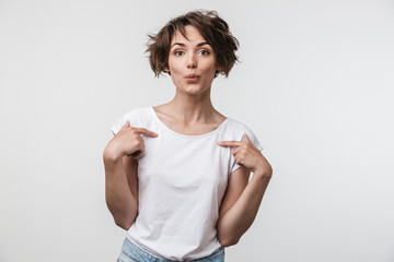 Portrait of joyful woman with short brown hair in basic t-shirt rejoicing and pointing fingers at...