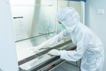 A scientist in sterile coverall gown using alcohol 70% and cleanroom wipes for cleaning Biological...