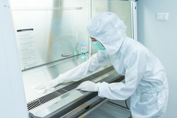 A scientist in sterile coverall gown using alcohol 70% and cleanroom wipes for cleaning Biological...