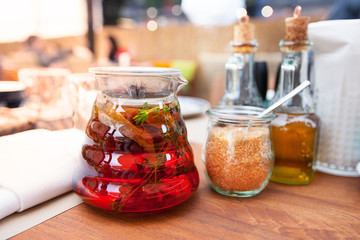 Glass teapot with fruit tea in a restaurant on wooden table. Glass jug with sangria in bar. Glass jug with organic fresh juice with fruit in cafe.