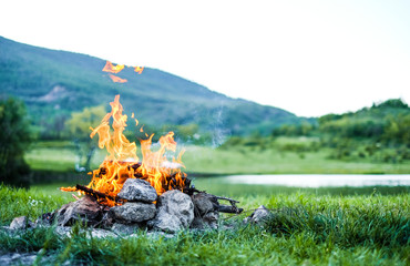 Burning fire in nature on the background of the lake The embers in the fire. Burning coal in the...