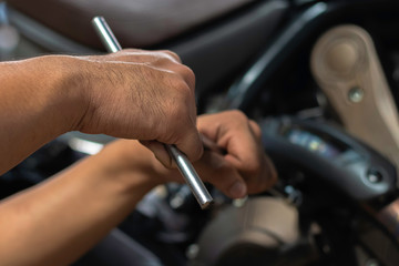 Naklejka premium Image is Close up,People are repairing a motorcycle Use a wrench and a screwdriver to work.