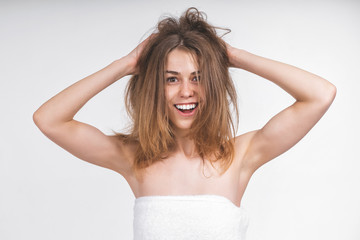 young nude girl in a towel with disheveled hair looks into the camera. Shows armpits. Shaved armpits. Beautiful smile, white teeth. Cheerful, mischievous. On an empty background.