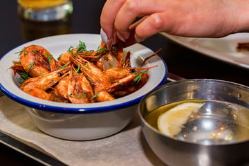 Close up hands of young woman eating shrimps in restaurant