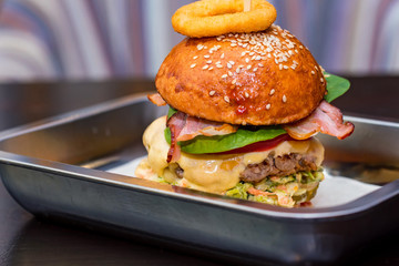 Close up tall tasty burger with cheese served on tray