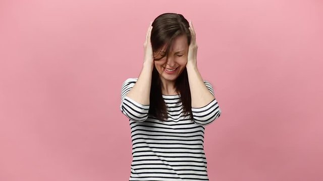 Irritated dissatisfied brunette young woman in striped shirt looking camera gesticulating say no bla-bla-bla isolated over pastel pink background in studio. People sincere emotions, lifestyle concept.
