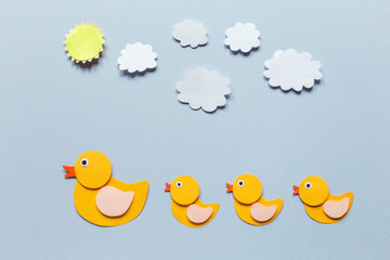Mom Duck and duckling of paper, blue background, three baby sun and clouds