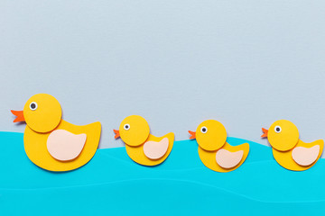 Mom Duck and duckling on the river of paper, blue background, three baby