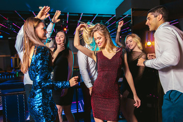 Young happy people are dancing in club. Nightlife and disco concept.